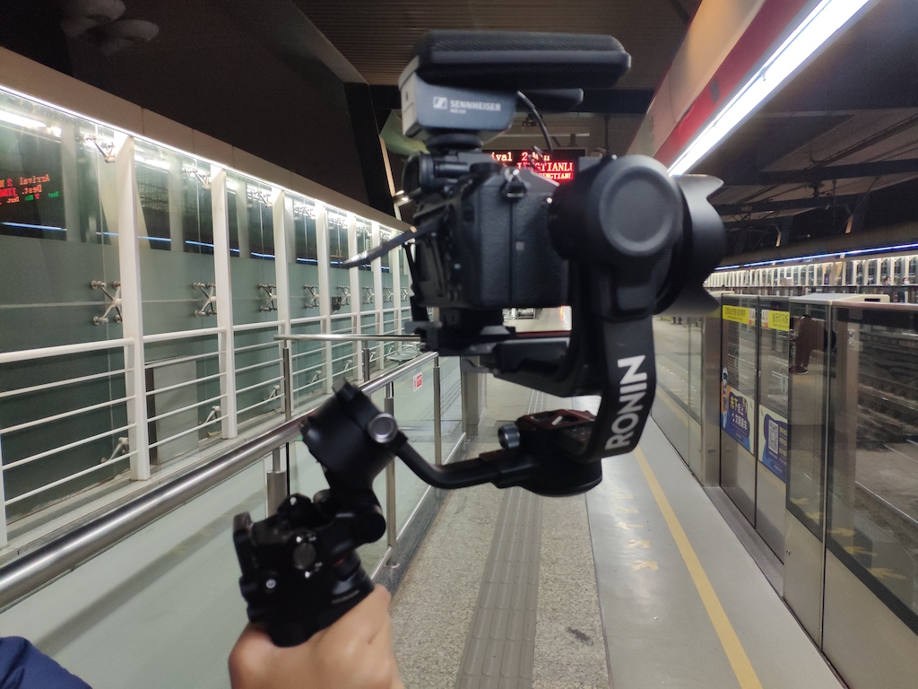 Camera being held with a gimbal filming in a train station